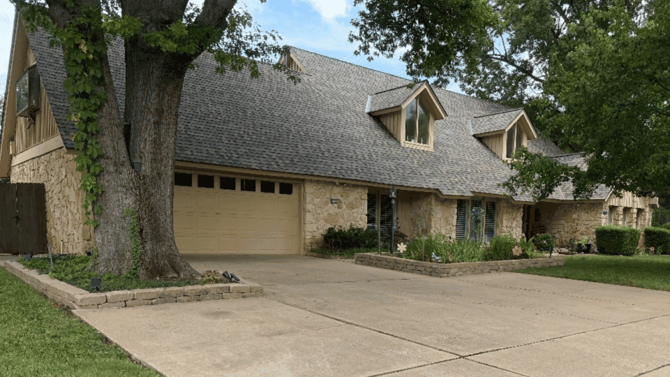 Front aerial of a stone-and-siding home with a new gray architectural shingle roof by Rlynt Roofing