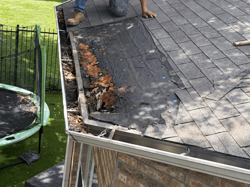 Rotted roof decking exposed along the eave at the gutter line during a leak repair