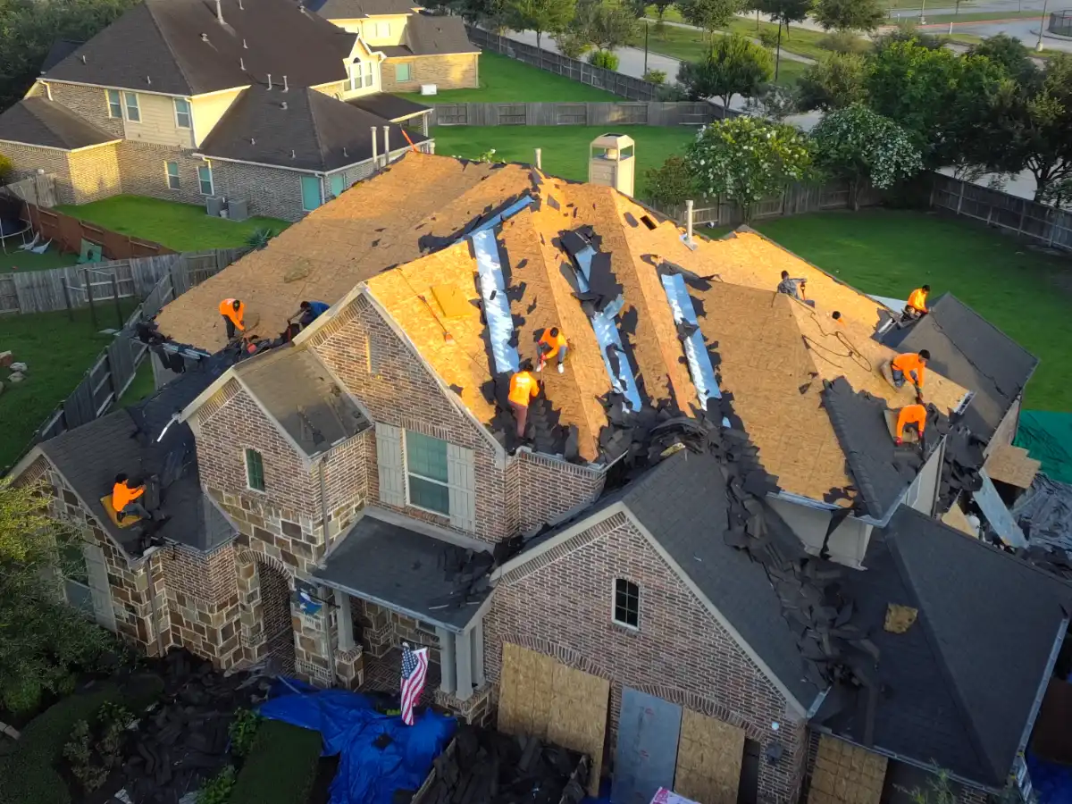 Rlynt Roofing crew tearing off an old roof to the deck at golden hour