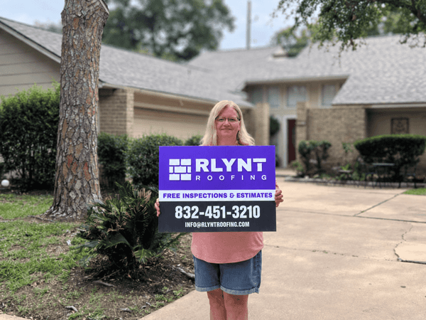 Rlynt Roofing customer holding a yard sign in front of their Cimarron home in Katy, TX